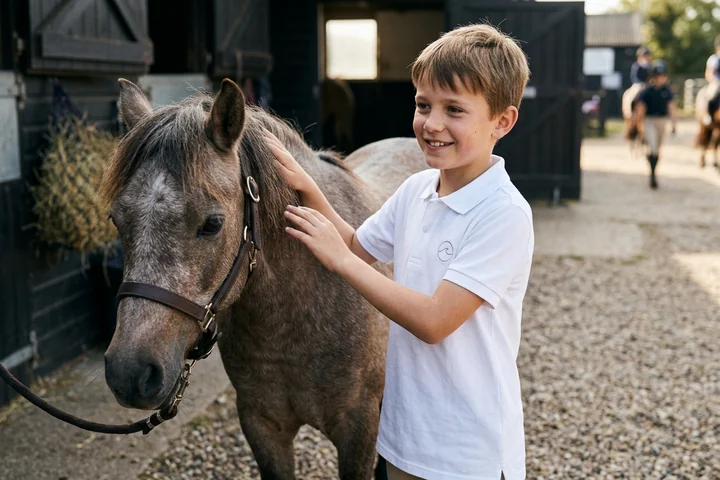 Niño de escuela de equitación con polo blanco